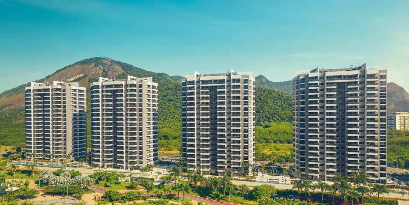 Fachada das torres do Astra Smart Facilities no Ilha Pura, com as montanhas da Barra da Tijuca ao fundo